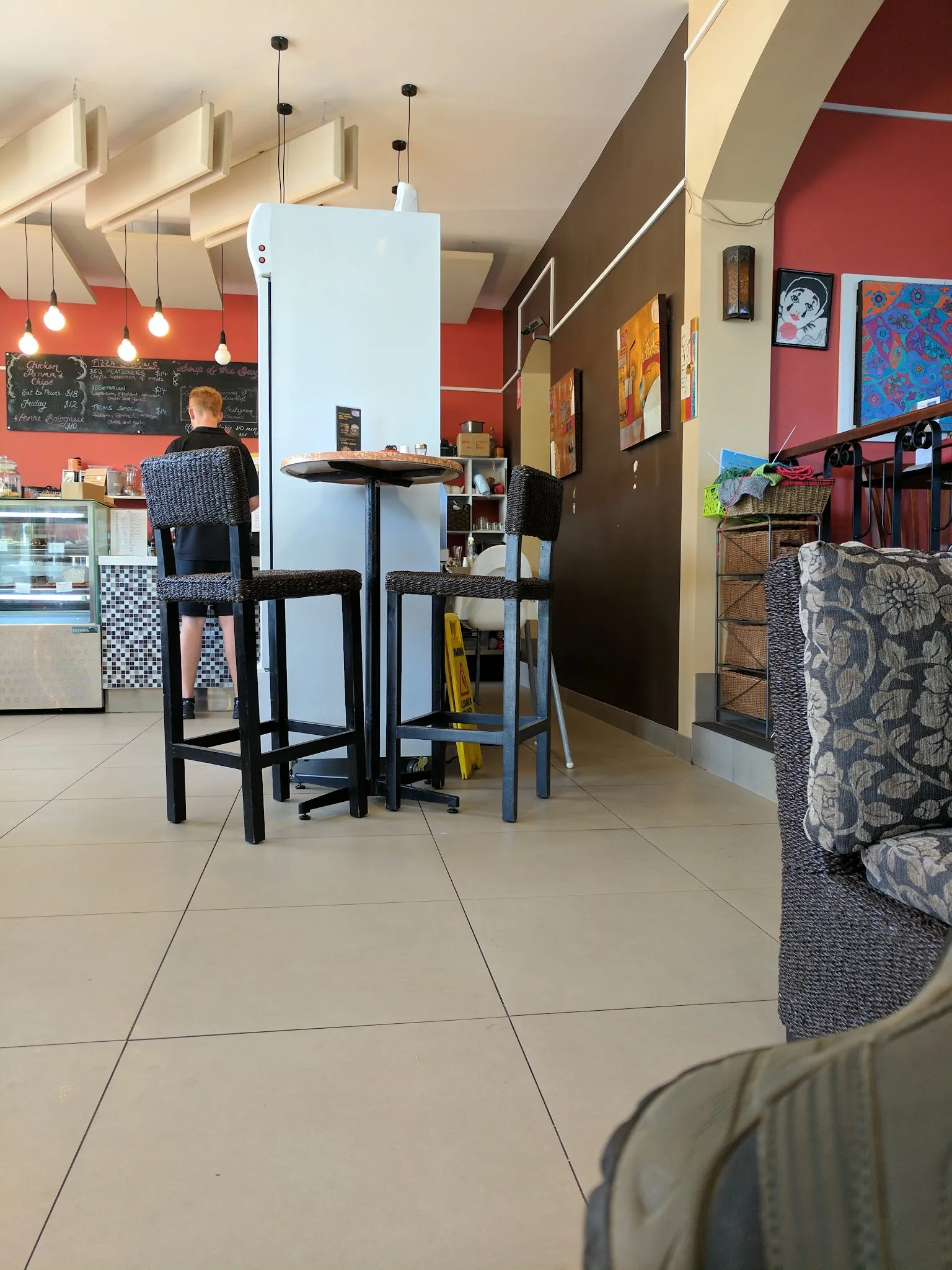 Trims cafe interior with red walls, artwork, bar stools and staff at counter