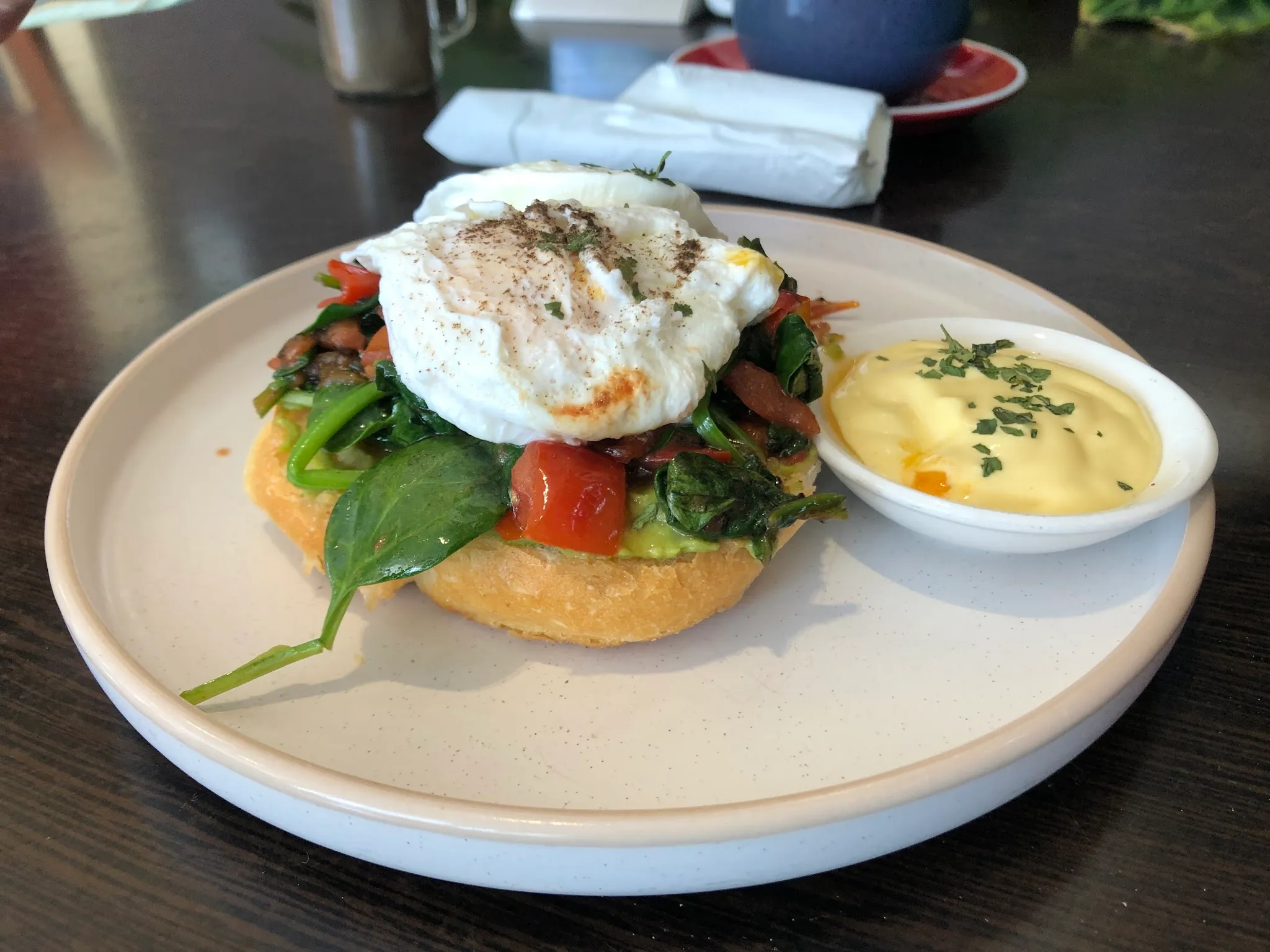 Poached egg on sauteed greens and toast with hollandaise, on ceramic plate
