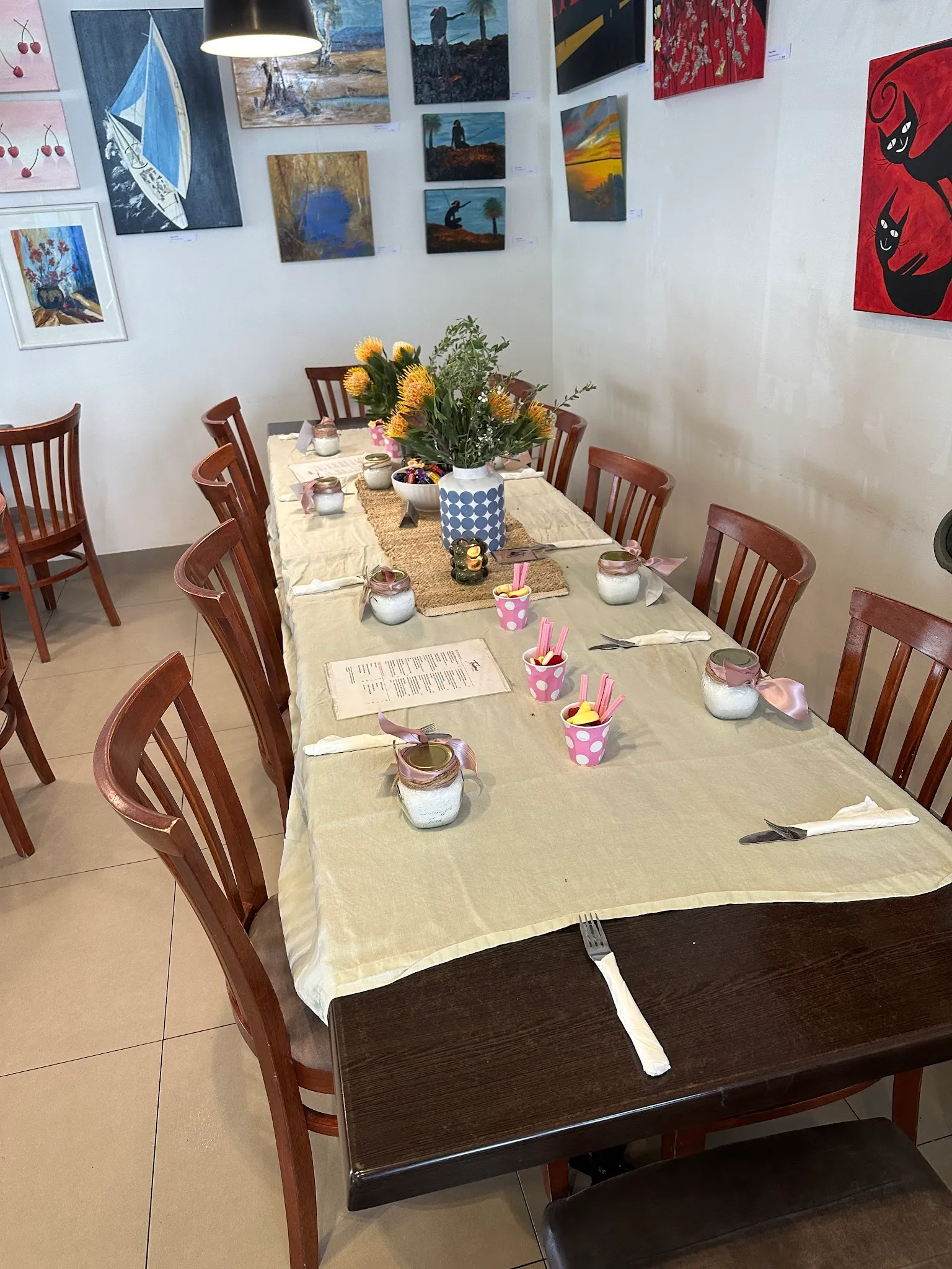 Trims dining room set for a special occasion with native flowers and local artwork on walls