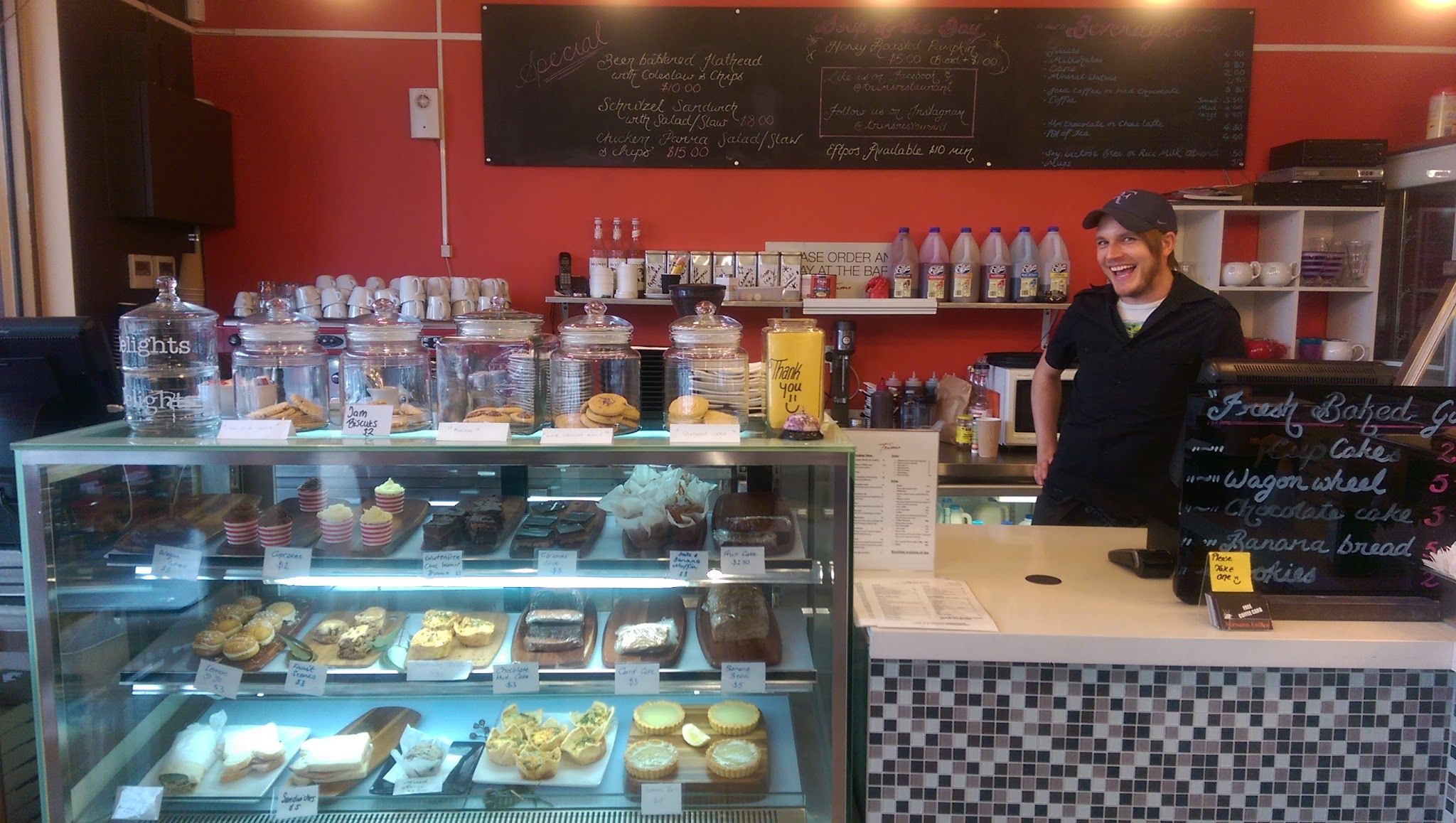 Trims service counter with baked goods display, chalkboard menus and smiling staff