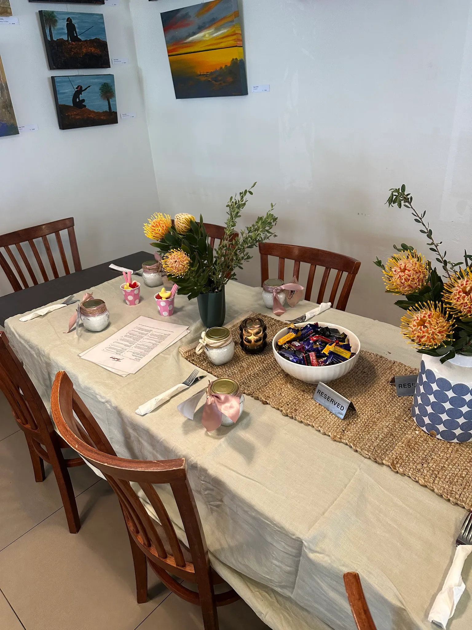 Trims dining table set for special occasion with native flowers, candles and local artwork
