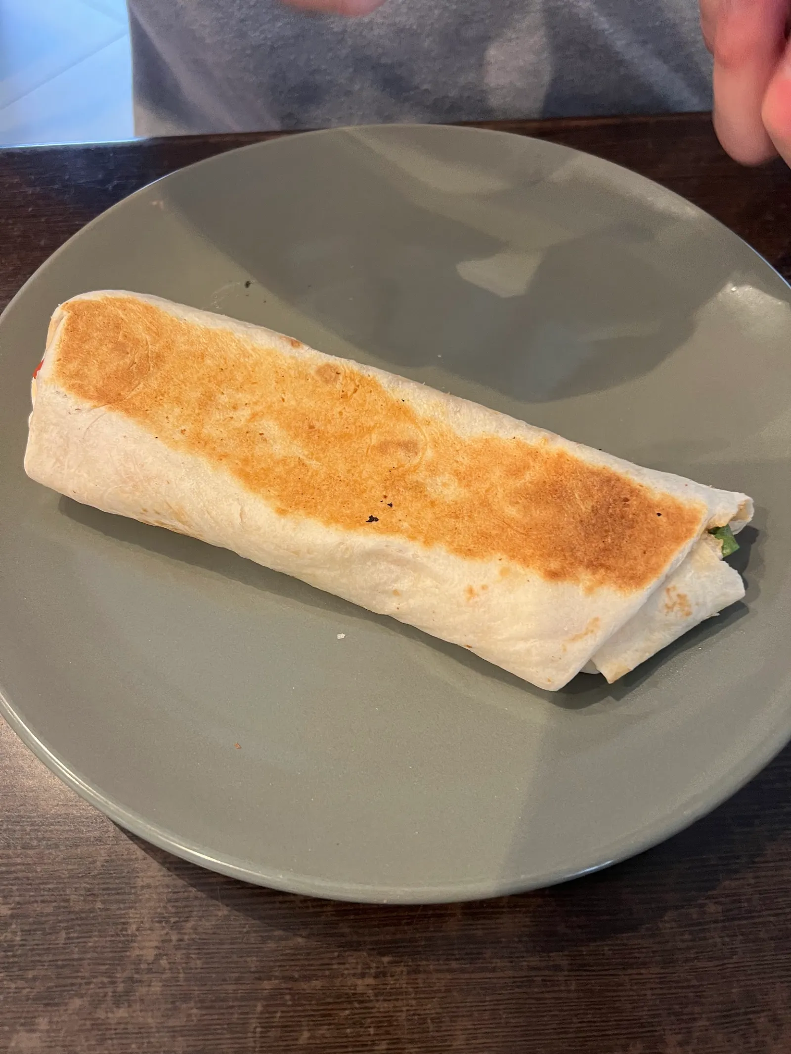 Grilled wrap on grey ceramic plate on timber table